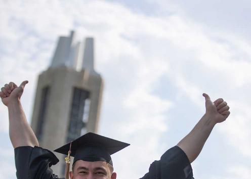 A graduation gives a thumbs up in front of the campenille